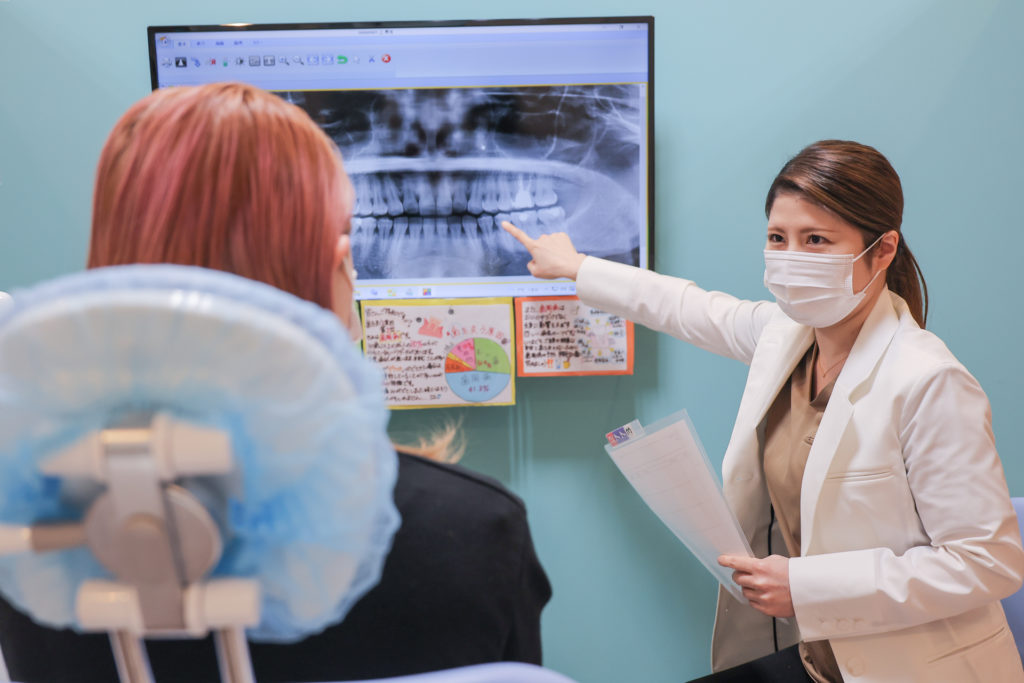 歯科医院でレントゲン写真について治療説明をする先生